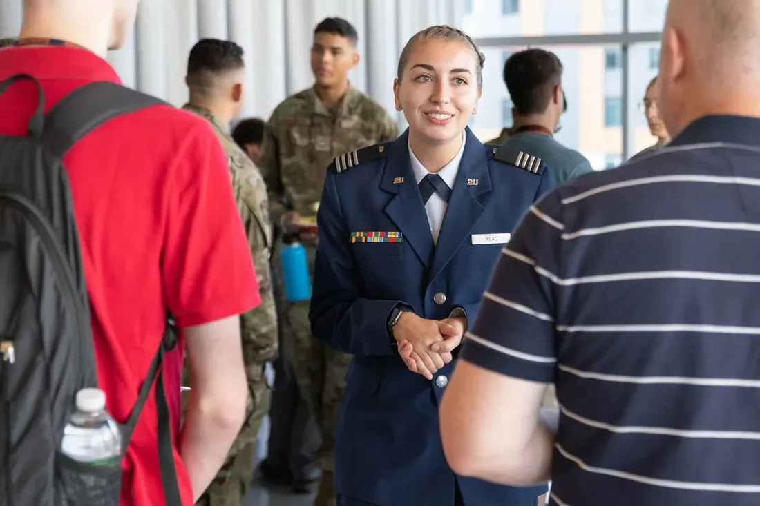 ROTC cadet smiling and speaking with people.