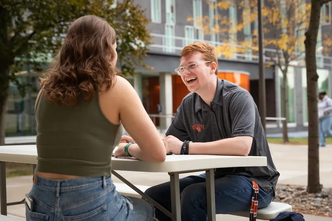 Two students sitting outside and talking.